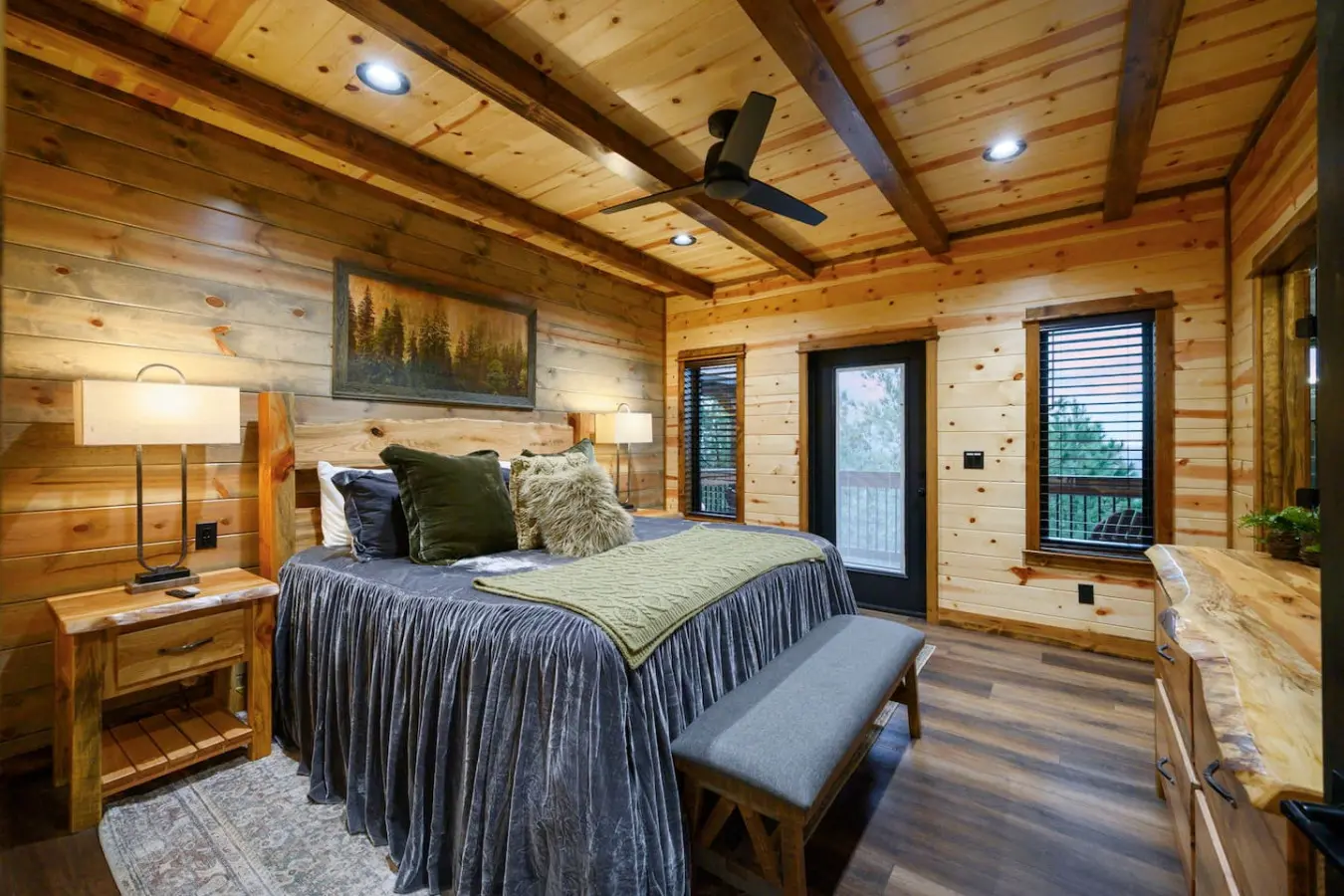 This beautiful master suite features exposed beam ceilings, multiple glass doors with mountain views, and rustic wood throughout.
