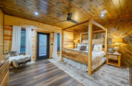 This gorgeous log bedroom features a massive four-poster bed, cozy seating area, and private balcony overlooking the mountains.