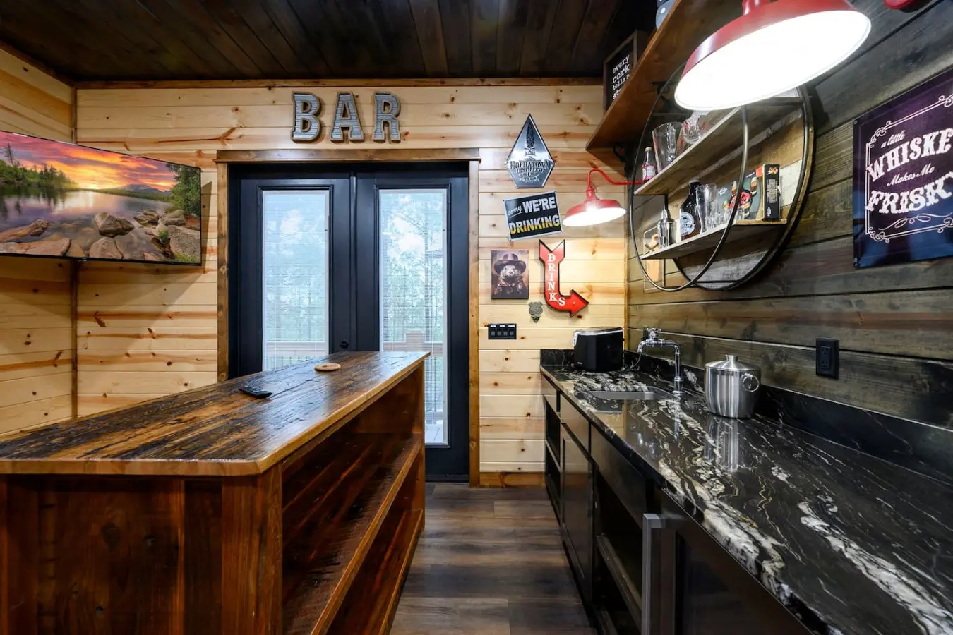 This custom bar space features rustic wood finishes, sleek black countertops, and direct access to the outdoor deck.