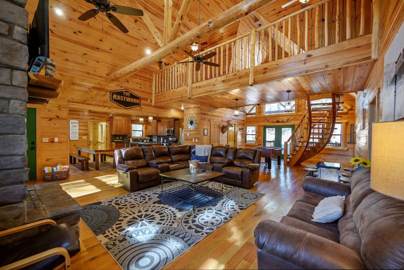 Our cabin's living room boasts a spacious and open layout, complete with a soaring ceiling and large windows. The comfortable furnishings and stone fireplace make this room a cozy and inviting space.