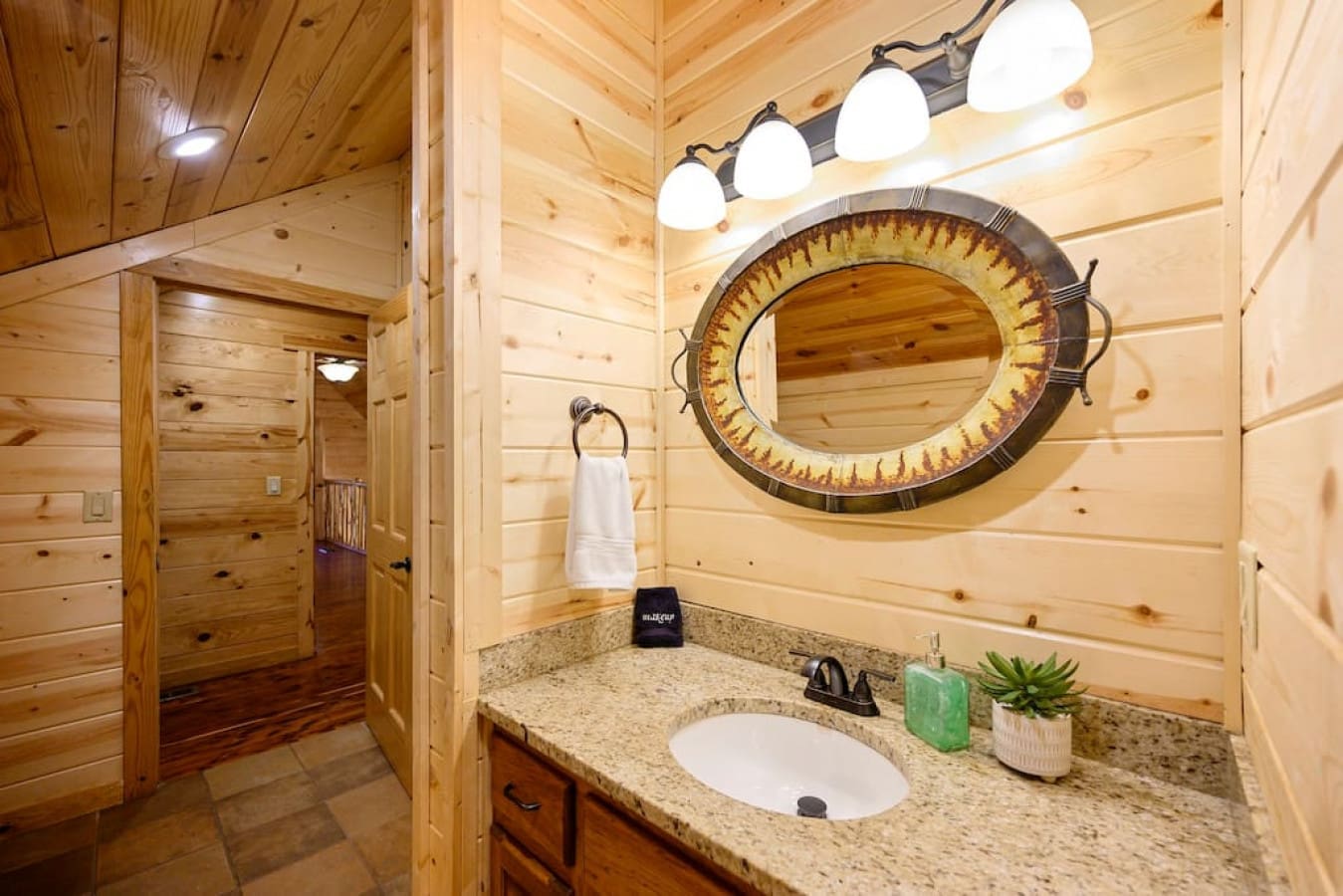 Elevate your daily routine with our well-appointed bathroom sink, featuring a sleek mirror, illuminated by soft lights, and a fresh, fluffy towel at your disposal.