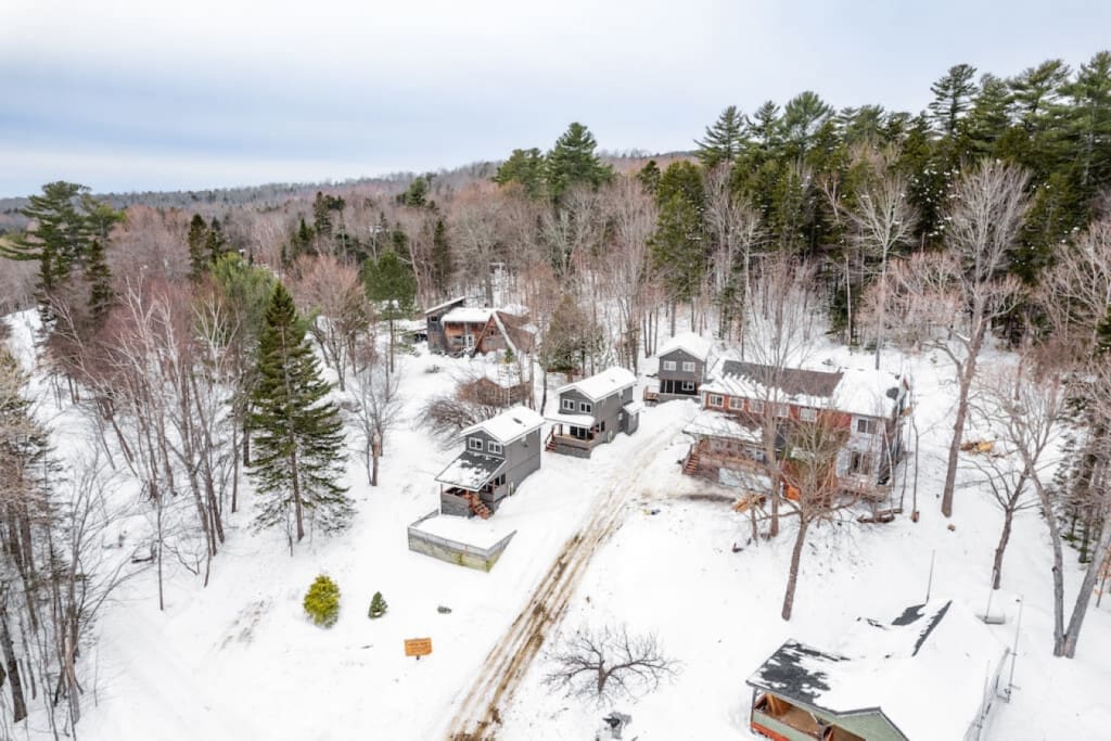 An aerial view showcases the cabin's rustic charm against the pure white backdrop of winter.