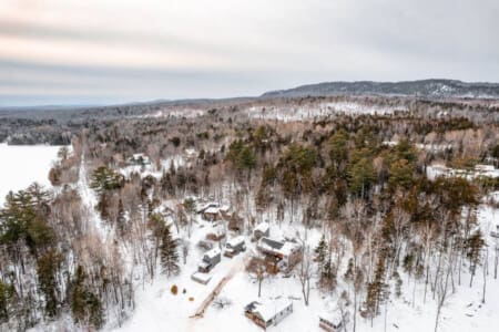 A bird's eye view reveals the cabin's snug embrace amidst the snowy expanse.