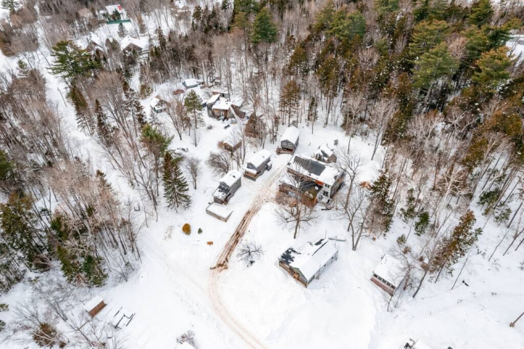 A bird's eye view reveals the cabin's snug embrace amidst the snowy expanse.