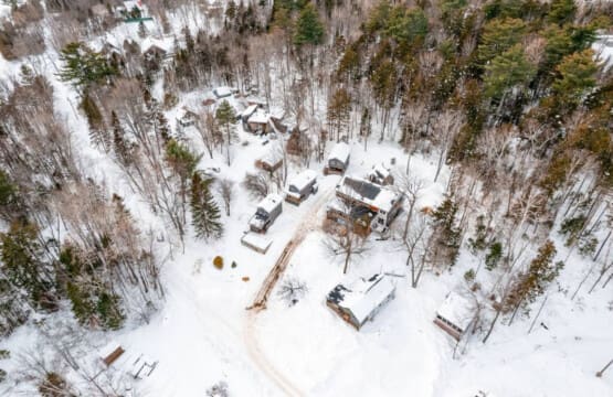 A bird's eye view reveals the cabin's snug embrace amidst the snowy expanse.