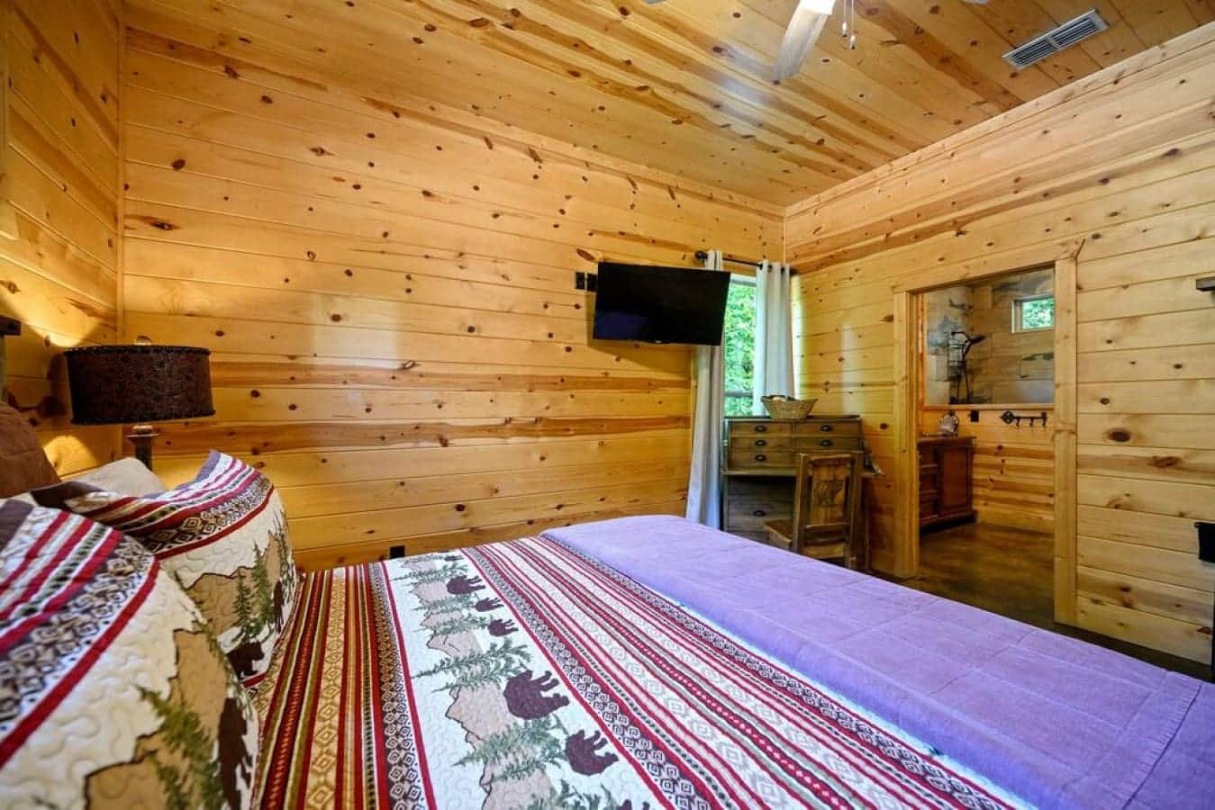 In the quiet embrace of this cabin bedroom, the essence of nature lingers, inviting you to sleep under the spell of peaceful serenity.