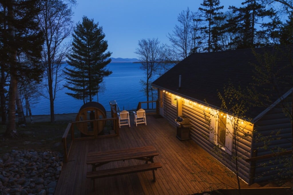 Soak in the barrel sauna while string lights shimmer over a mirror-still lake at dusk.