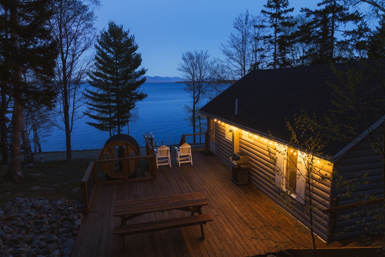 Soak in the barrel sauna while string lights shimmer over a mirror-still lake at dusk.