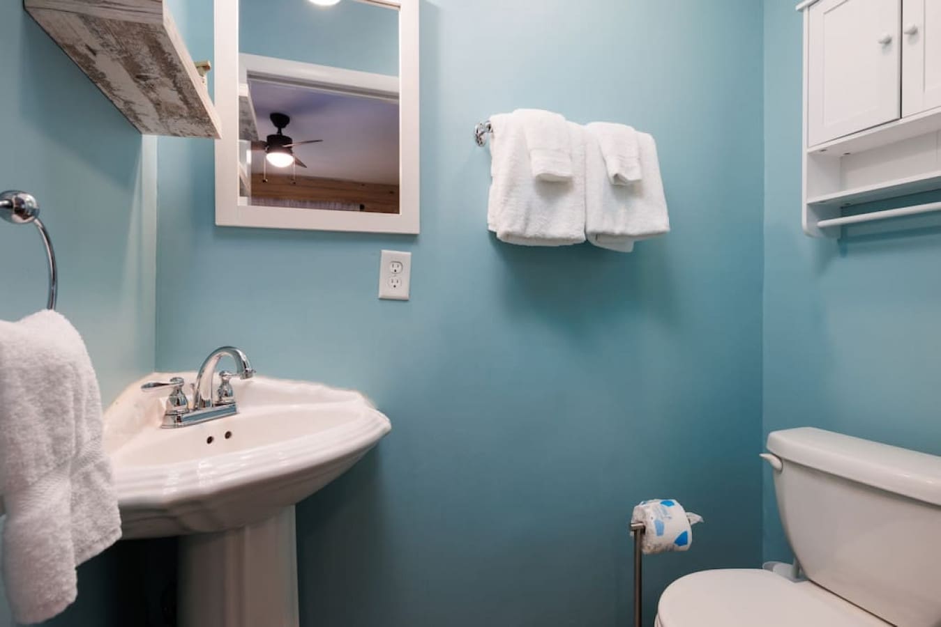 This bathroom is giving major vacation vibes with that stunning turquoise wall and spotless white fixtures.