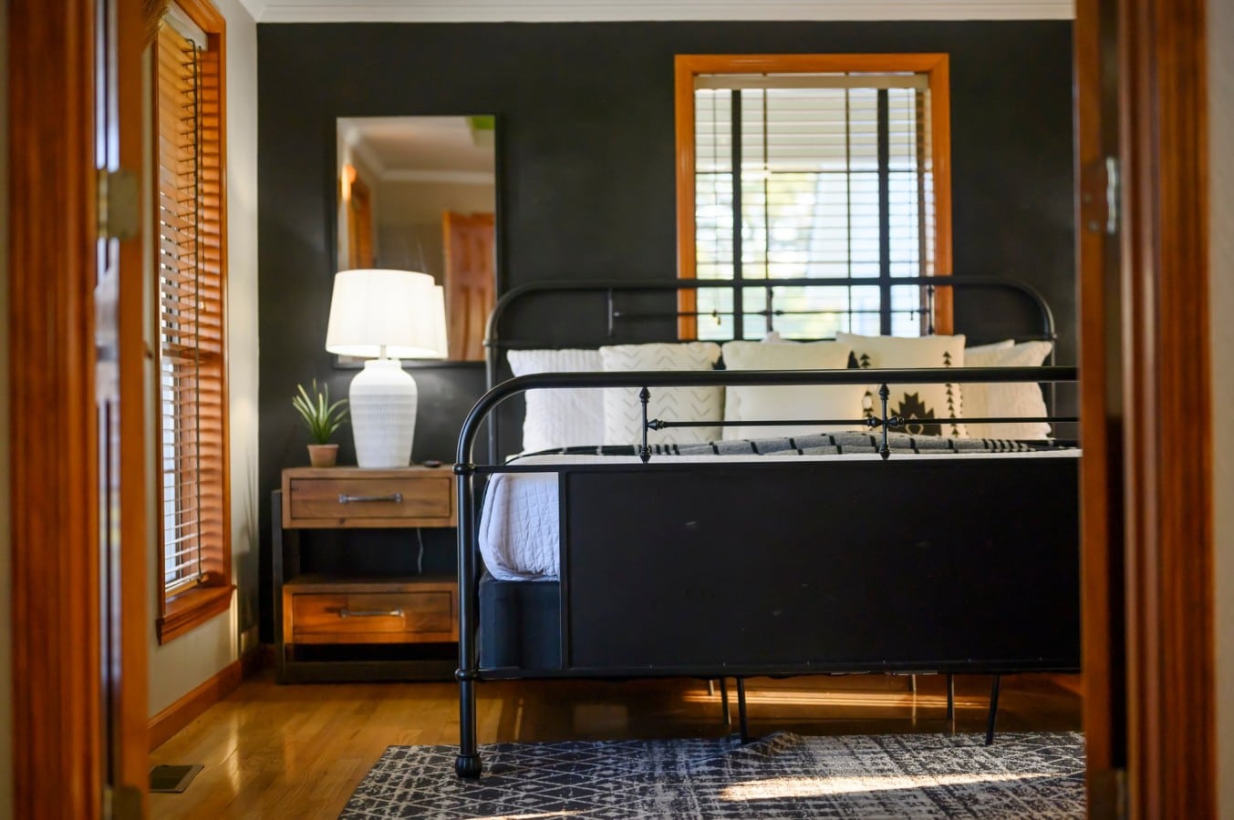 Bedroom view through double doors with black metal bed frame.