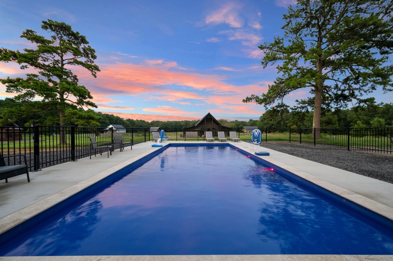 Poolside angle showing the basketball hoop and sunset sky.