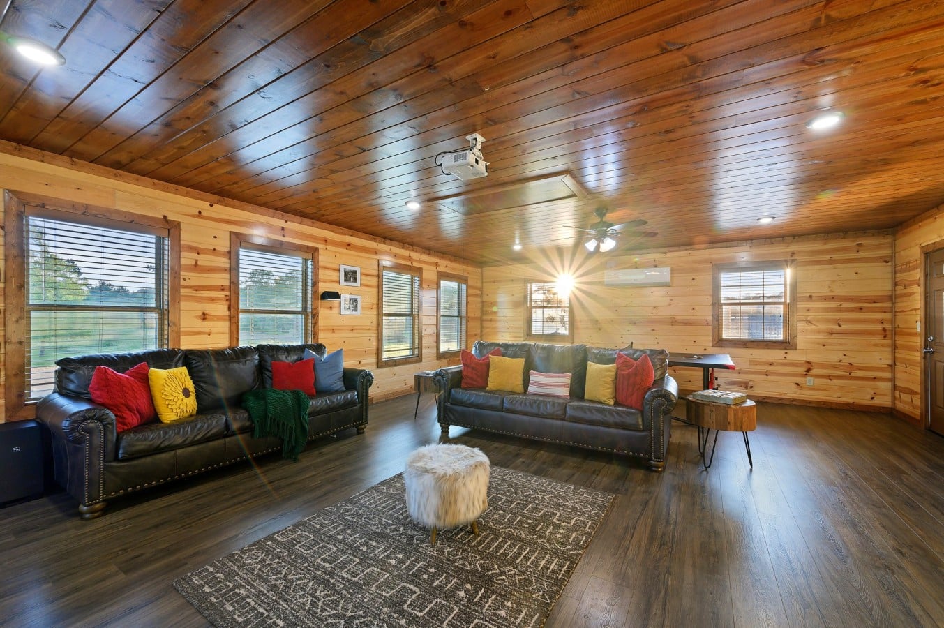 Wide wood-paneled game room with sofa seating and pool table.