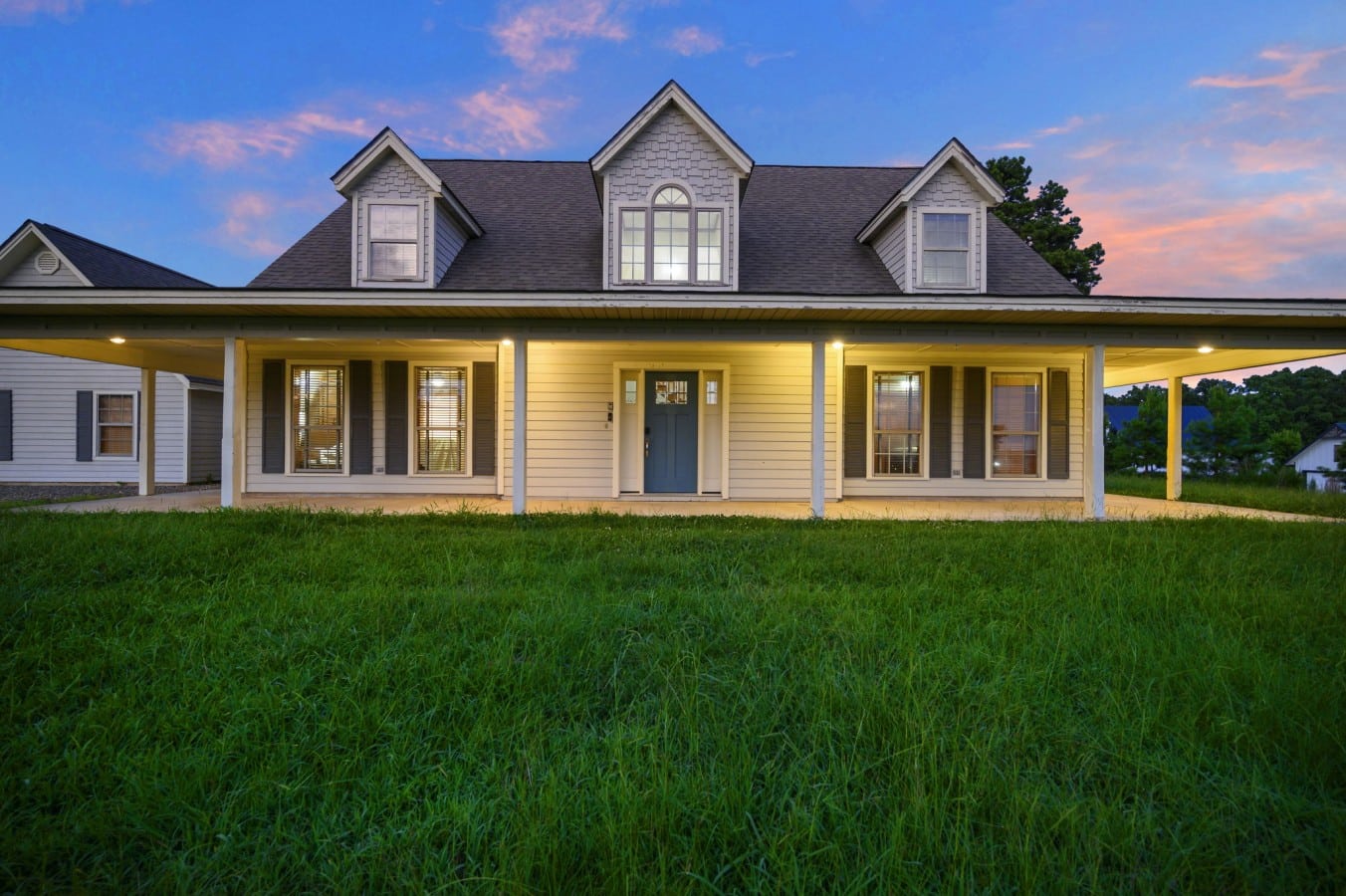 Front exterior with long porch and bright green lawn.