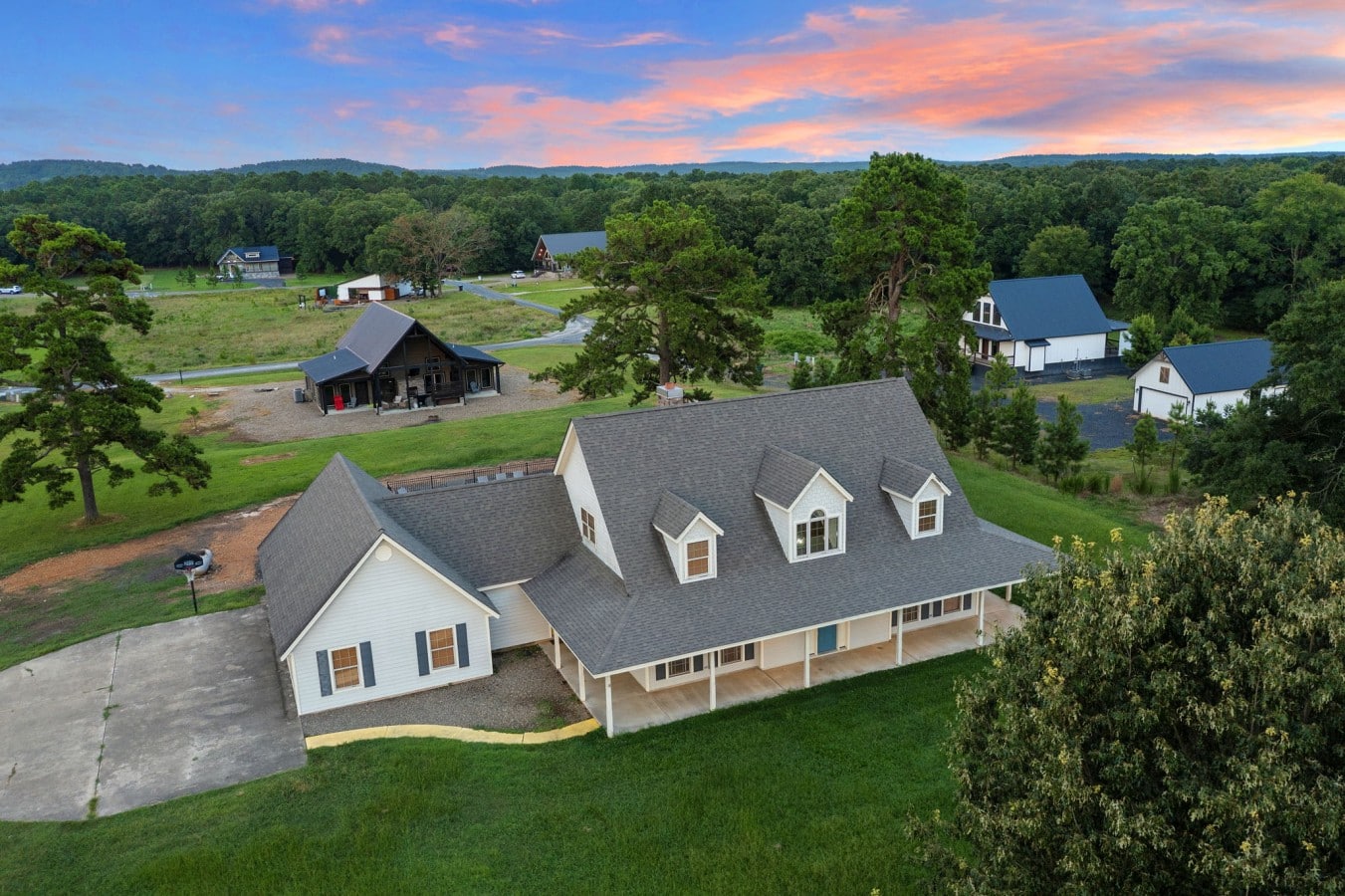 Aerial front view showing the long porch and open setting.