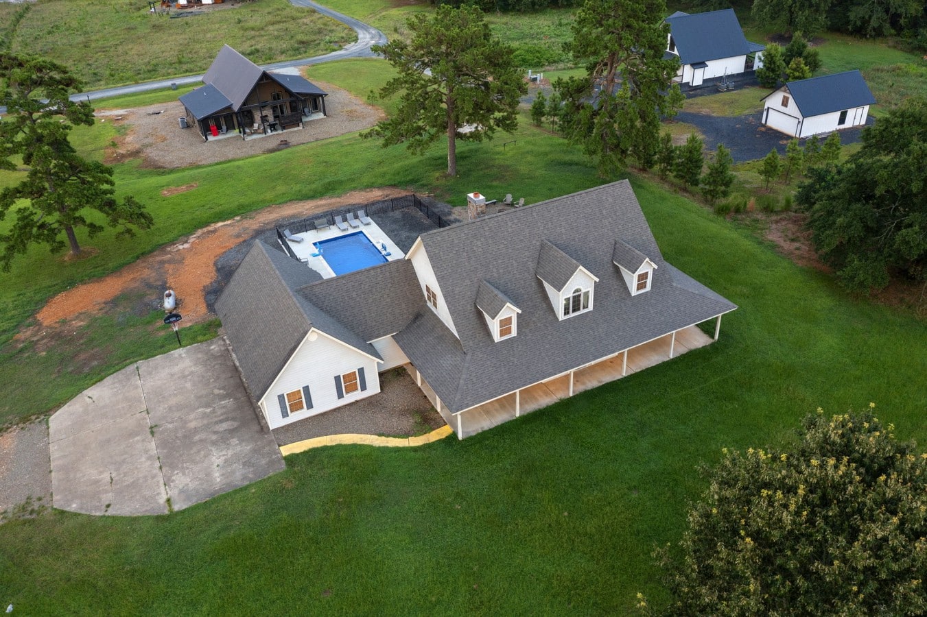 Drone angle showing the driveway, pool, and outdoor spaces.