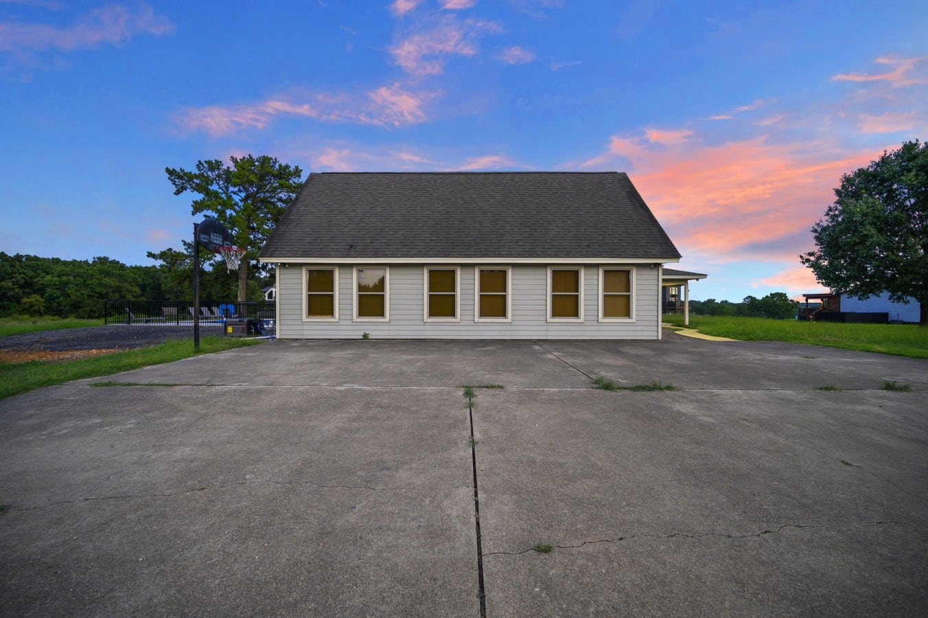 Front exterior with large driveway and open country setting.