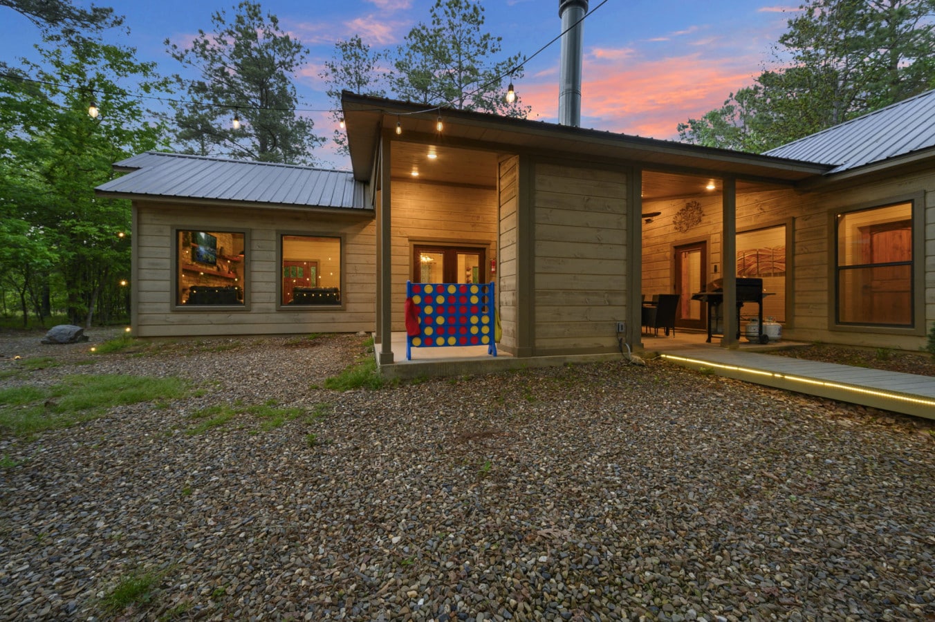 Beautiful evening view of the cabin's exterior and outdoor living areas lit with string lights.