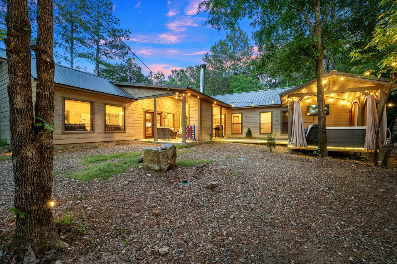 Wide evening view of the cabin, highlighting the cozy and well-lit outdoor spaces.