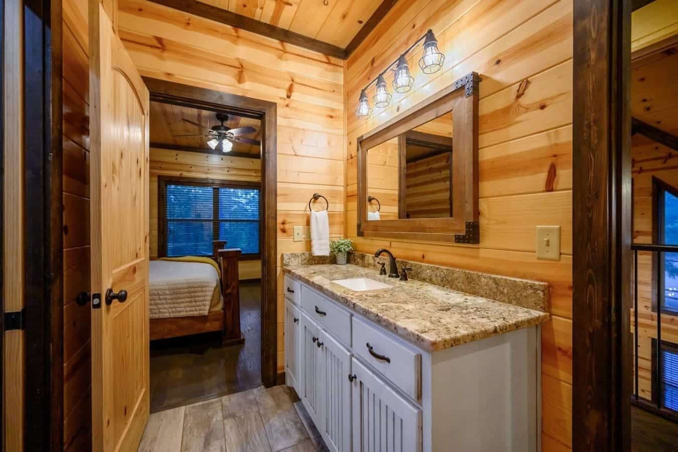 This bathroom perfectly nails that cabin vibe—rough wood walls, granite countertop, dual mirrors, and those vintage pendant lights all coming together to make getting ready feel like part of the whole relaxing experience.