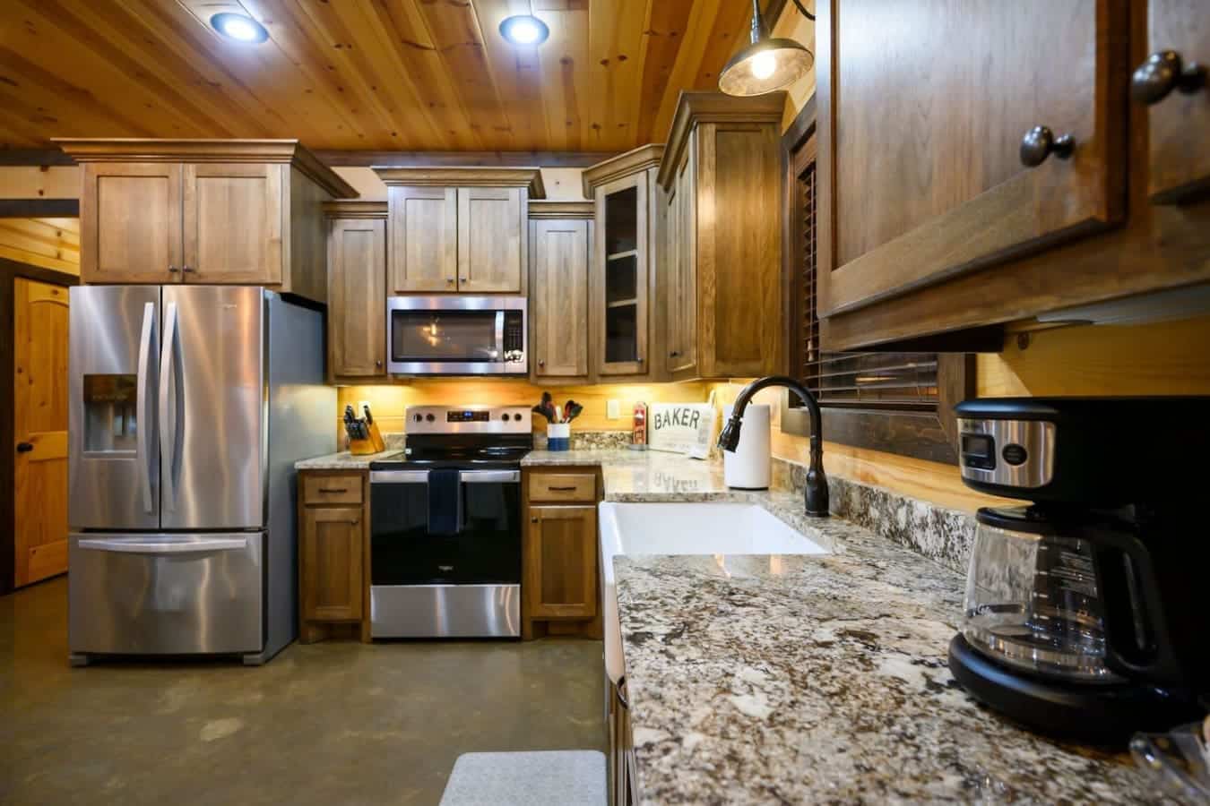 You've got granite countertops, stainless steel appliances, and that warm wood ceiling framing everything—this kitchen is basically built for actually enjoying cooking while you're supposed to be relaxing.
