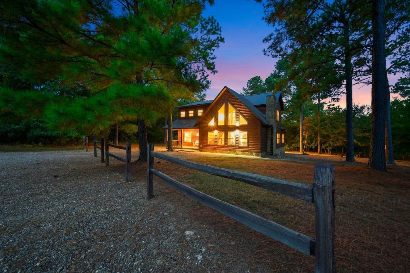 The cabin glows like a warm beacon nestled in the towering pines at twilight—this is what "getting away from it all" actually looks like.