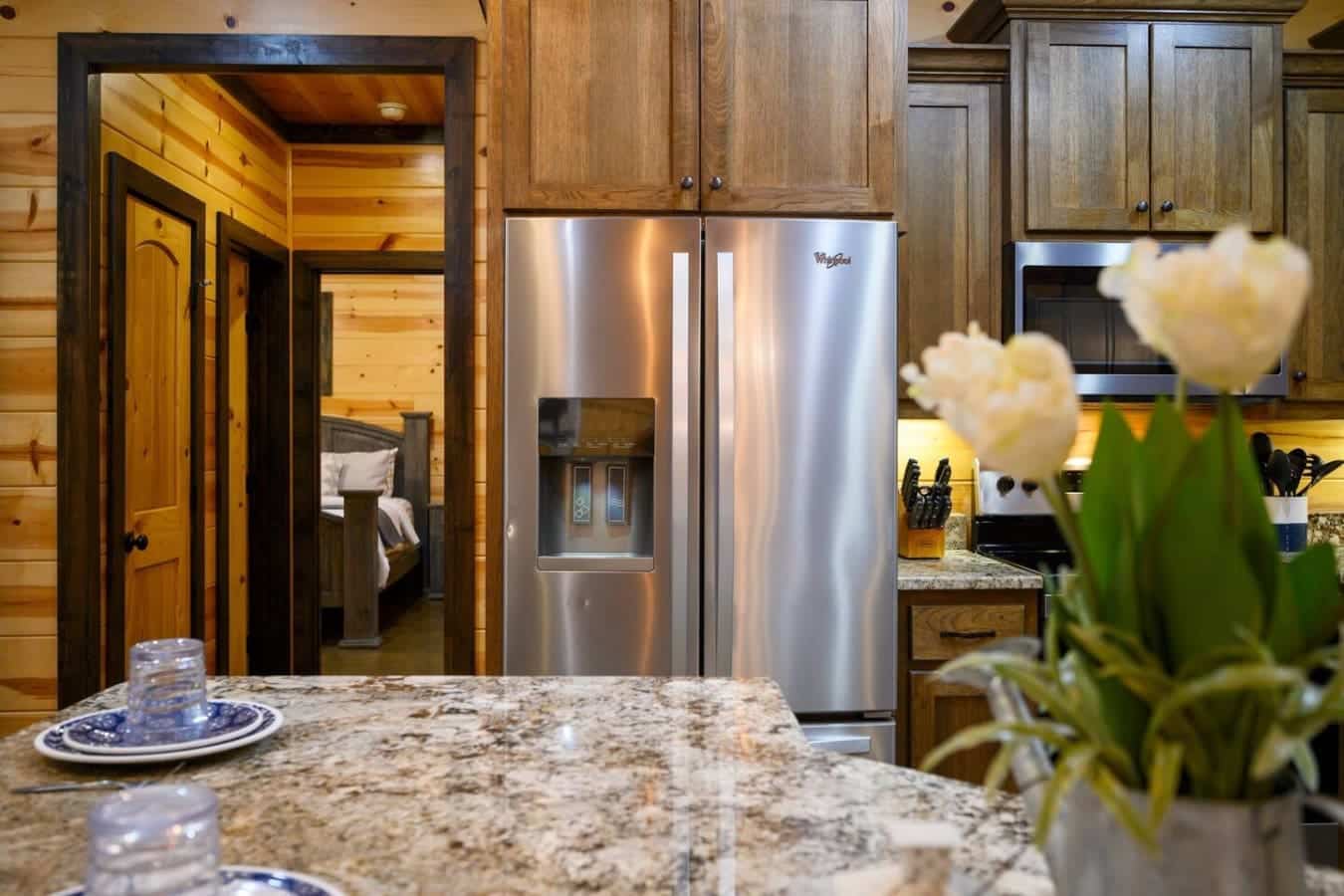 The stainless steel refrigerator and upper cabinetry gleam against the warm wood tones, while that granite countertop and open layout make the kitchen feel like the natural gathering spot for your whole crew.