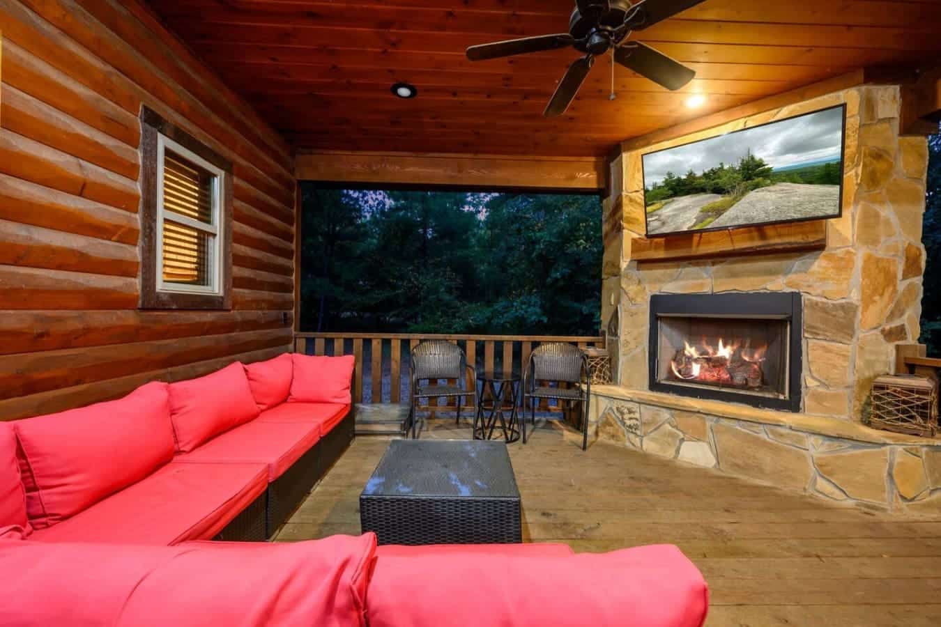 This covered porch is basically an outdoor living room—cozy seating, a real fireplace, and those dark woods stretching out in front of you make it feel like you're sitting in your own private retreat.