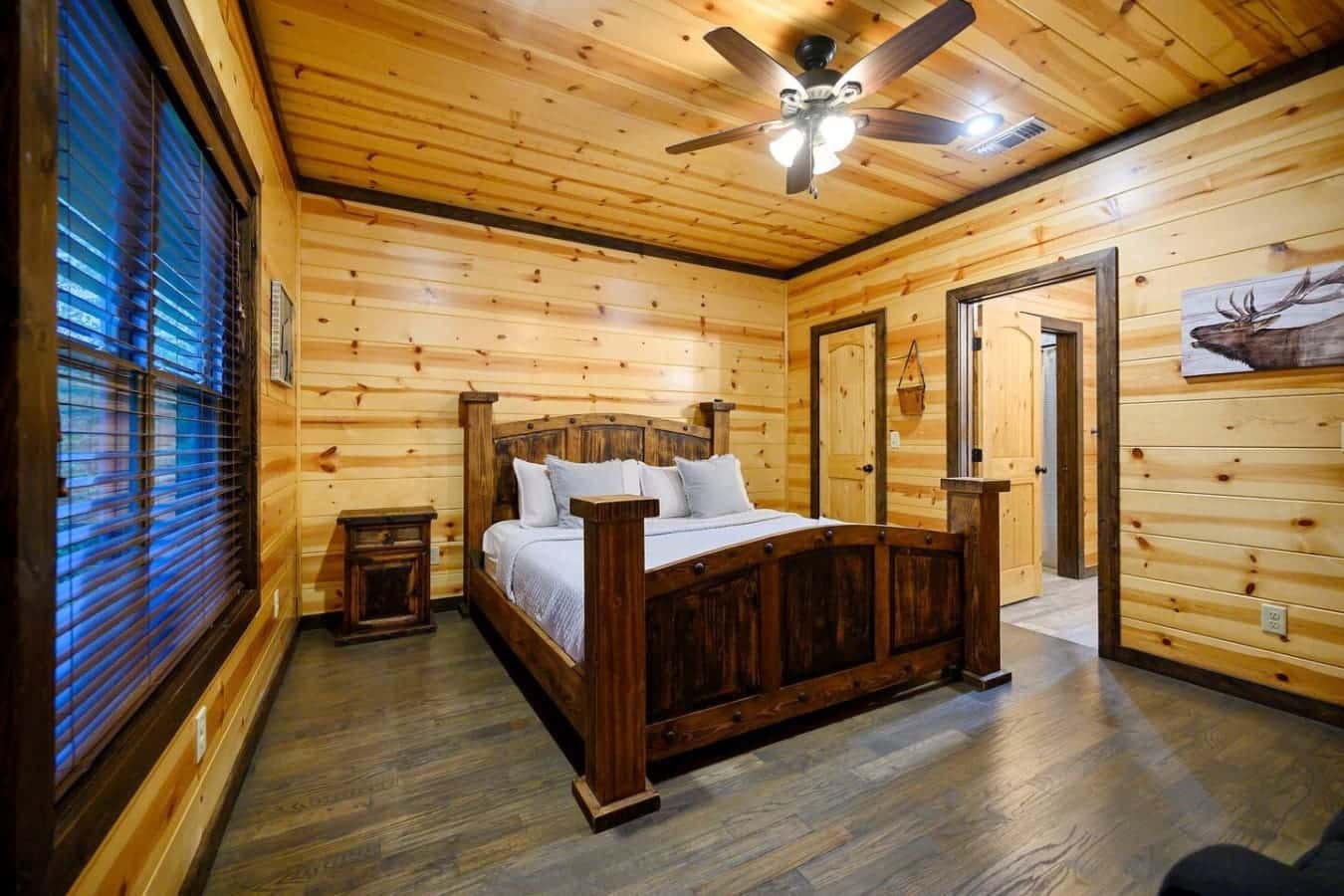 The dark wood four-poster bed perfectly anchors this wood-wrapped bedroom, giving you that authentic lodge sleeping experience without sacrificing comfort.