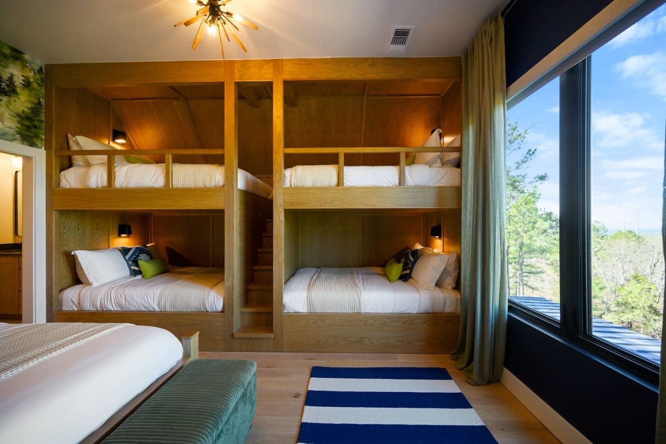 This gorgeous bunk room with its custom wooden sleeping nooks and those huge windows overlooking the forest is basically the ultimate sleepover setup—everyone gets their own cozy spot, and the views are honestly unbeatable.