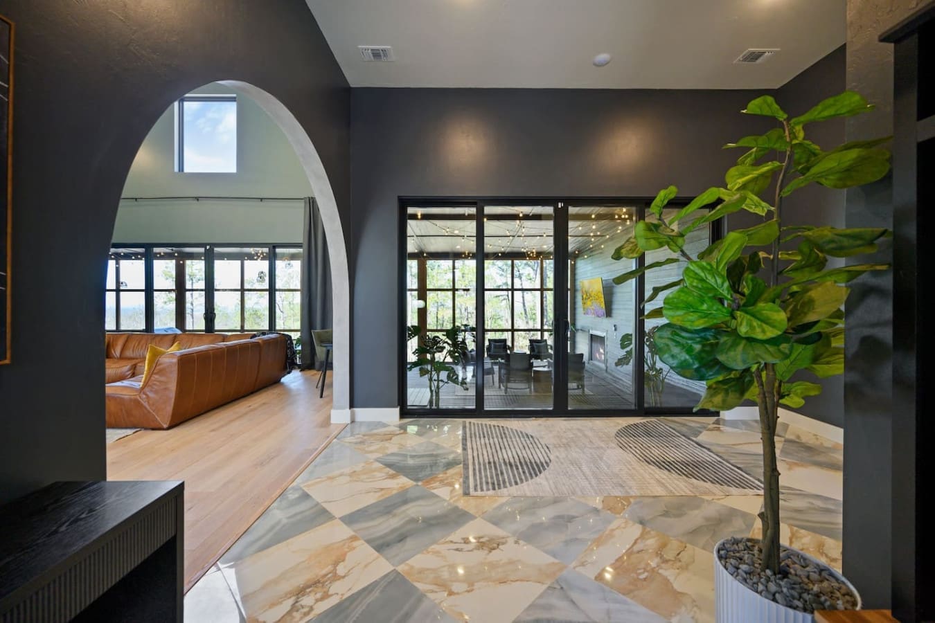 This stunning entryway with its dramatic arched doorway, polished marble floors, and those floor-to-ceiling black-framed doors opening onto the deck basically sets the tone for the whole place—modern, sophisticated, and totally ready to blur the line betw