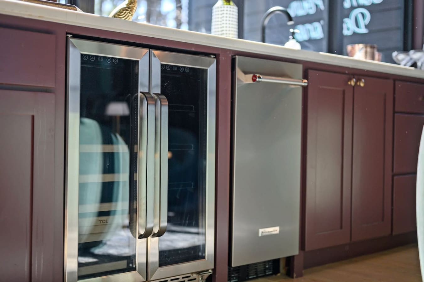 This high-end kitchen setup with its stainless steel appliances and rich burgundy cabinetry is basically a chef's dream—everything you need to whip up something amazing while those sleek finishes and warm wood tones keep the whole space feeling inviting.