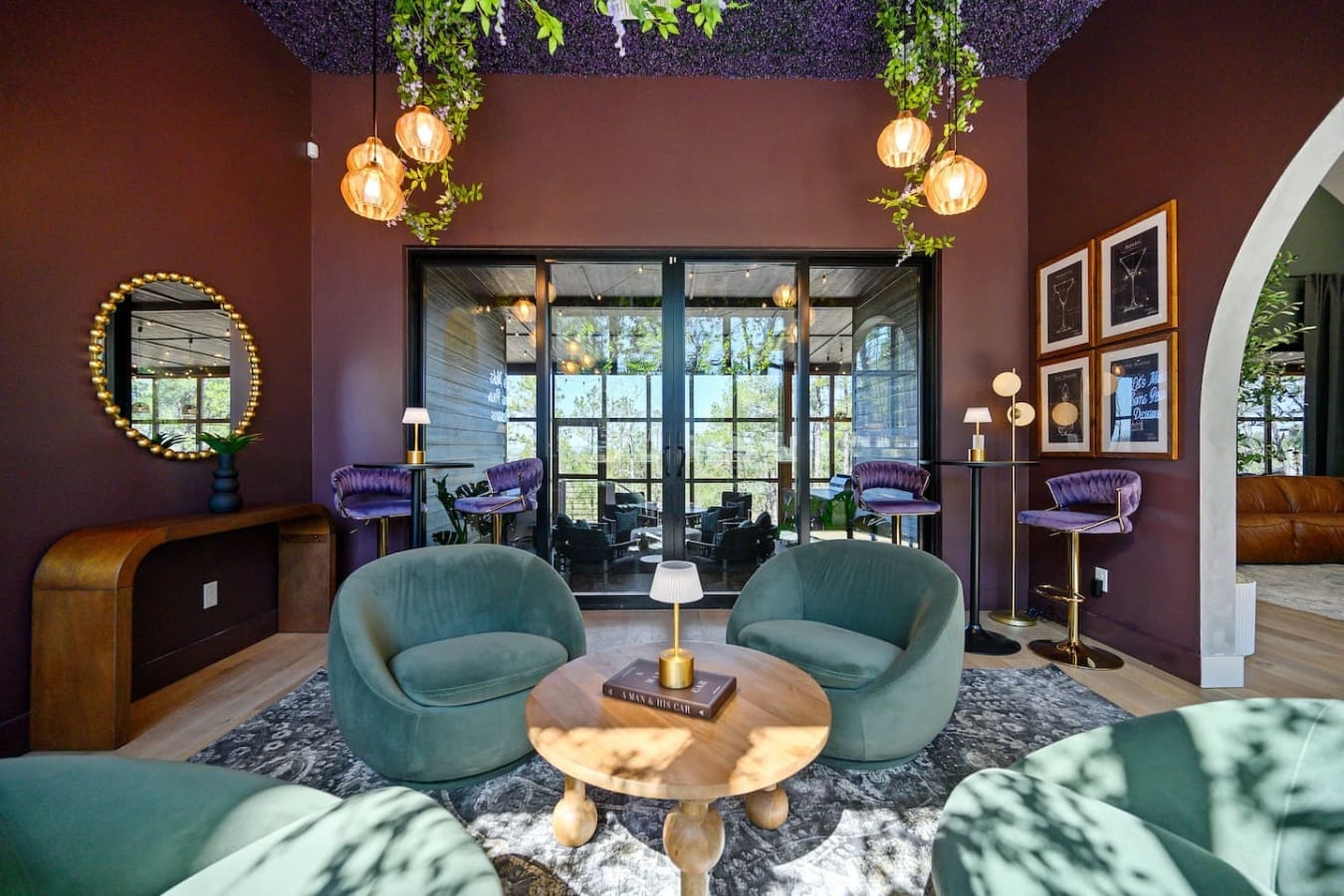 This moody burgundy lounge with those cushy teal chairs and hanging greenery feels like the perfect hideaway to sink into while gazing out at the forest through those massive glass doors.
