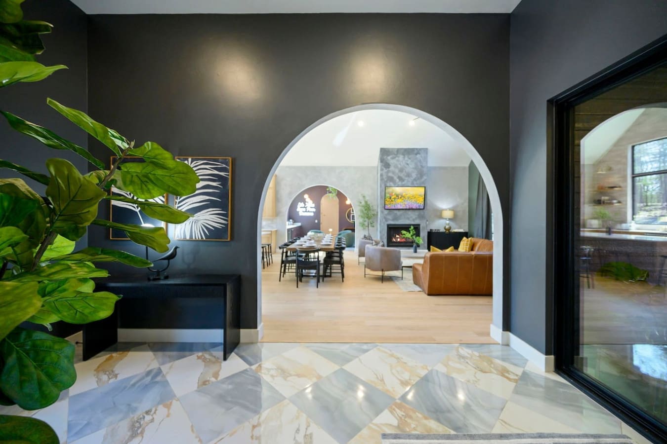 Walking through this stunning arched entryway with the polished marble floors and those huge black-framed glass doors feels like stepping into a gallery, and suddenly you're face-to-face with this massive open-concept living space that just screams modern