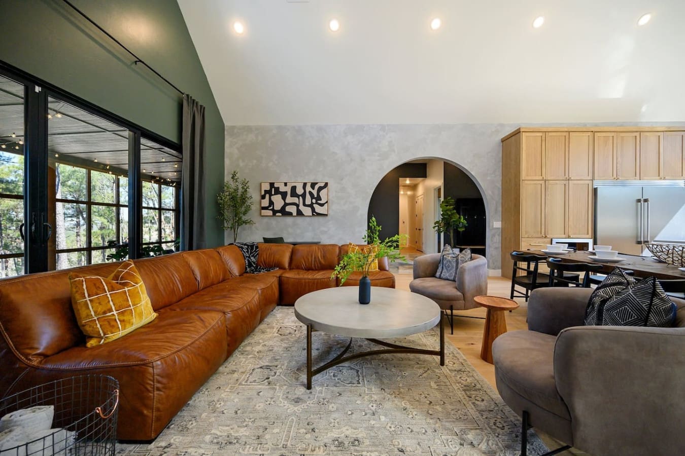 This open-concept living space is basically the perfect setup for hanging out—you've got that stunning cognac leather sectional, a round marble coffee table for gathering around, those cozy accent chairs, and enough natural light pouring in to make the wh