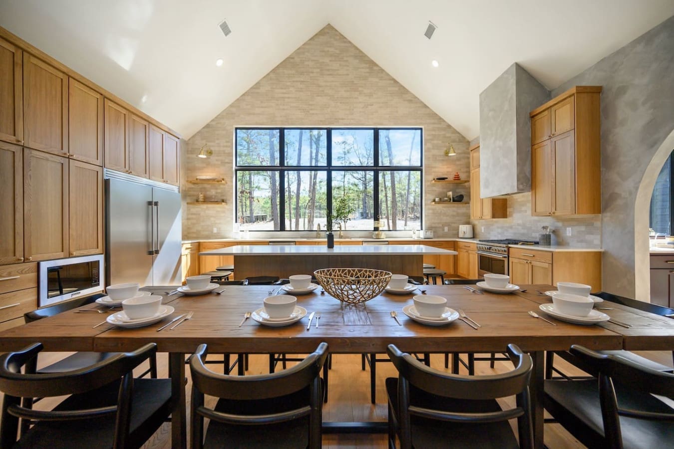 This soaring kitchen with its cathedral ceiling, massive picture windows framing the forest, and that gorgeous wood island is basically the heart of the home—perfect for cooking up something amazing while the trees become your dinner guests.