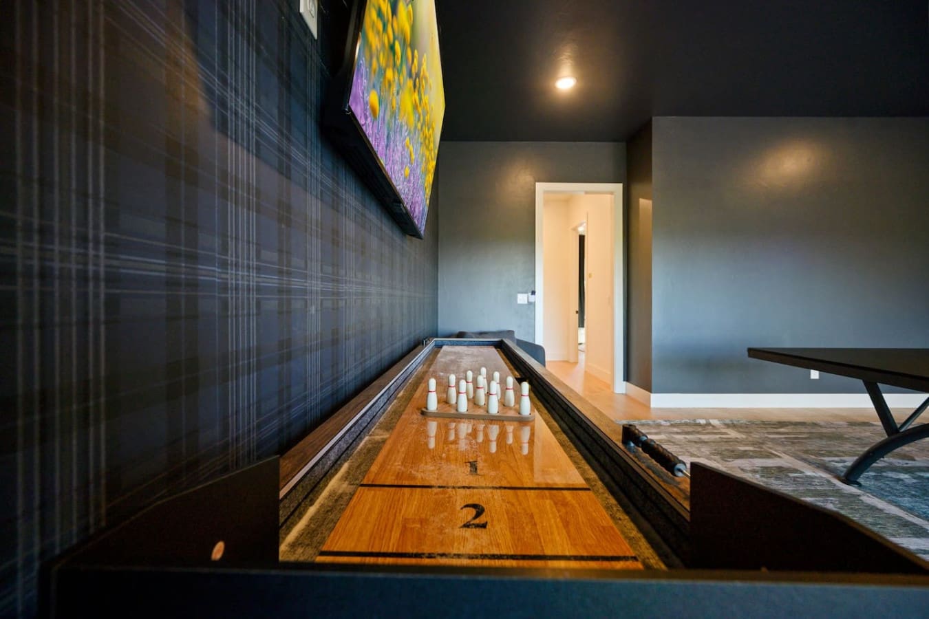 This shuffleboard setup is perfect for a competitive night in with friends, especially with that moody ambiance and the glowing display above keeping the energy going.