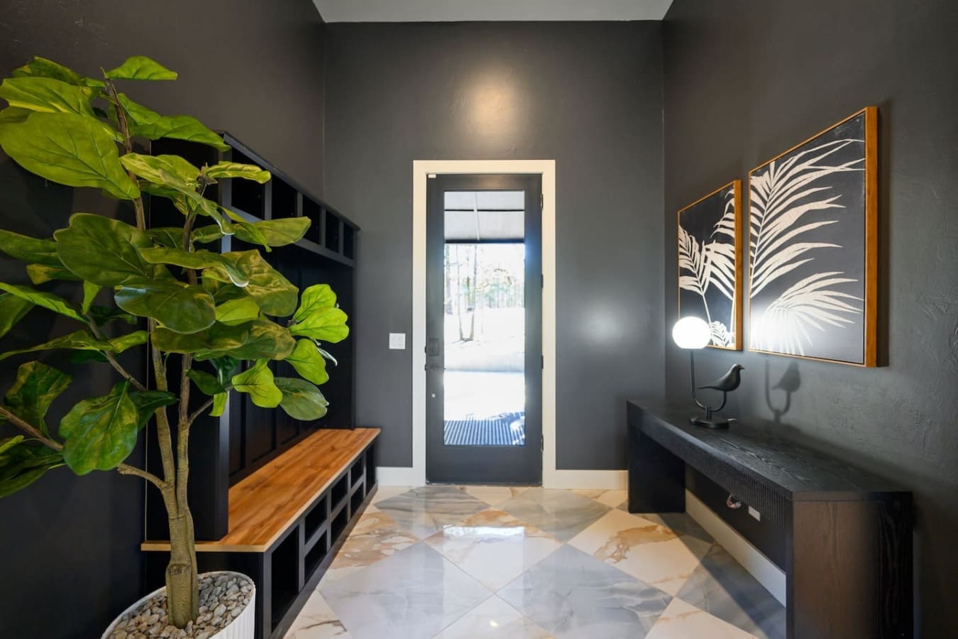 This moody entryway with its sleek black walls, natural light spilling through that glass door, and those botanical art prints basically sets the perfect tone for a stylish modern escape—it's giving gallery vibes meets cozy retreat.