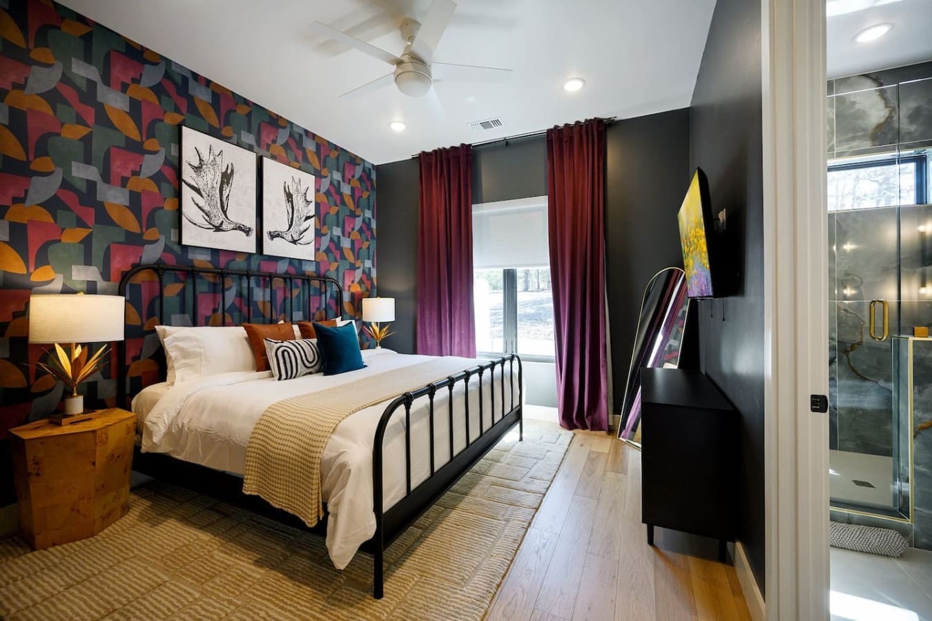 This master bedroom is a total showstopper with that bold patterned wallpaper, a sleek iron bed frame, and those gorgeous burgundy curtains framing the windows perfectly.