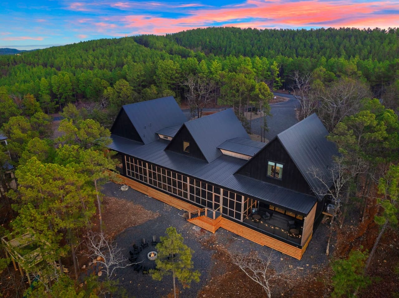 This striking modern retreat with its dramatic black exterior and soaring rooflines sits nestled perfectly in the forest, looking like something out of an architectural magazine while still feeling totally at home surrounded by all those towering pines.