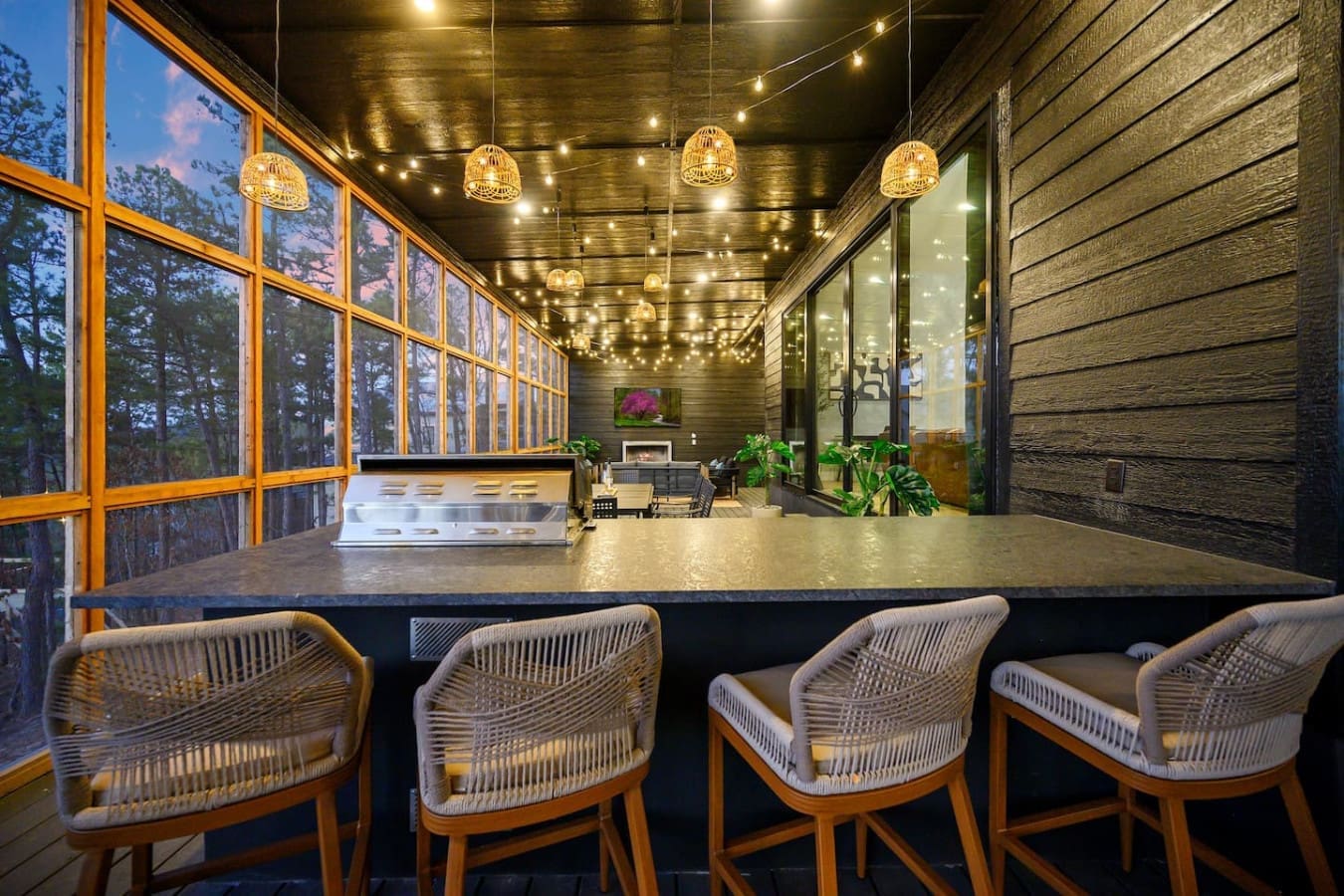 This sleek indoor bar area with those woven bucket chairs and pendant lighting is the perfect spot to gather and chat while taking in the twilight views through all those floor-to-ceiling windows.