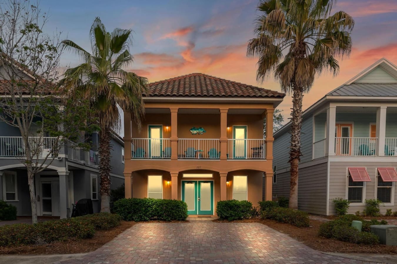 This charming two-story beauty with its warm terracotta facade and turquoise doors is basically the definition of "So Stinkin Cute" the moment you pull up to that brick driveway.