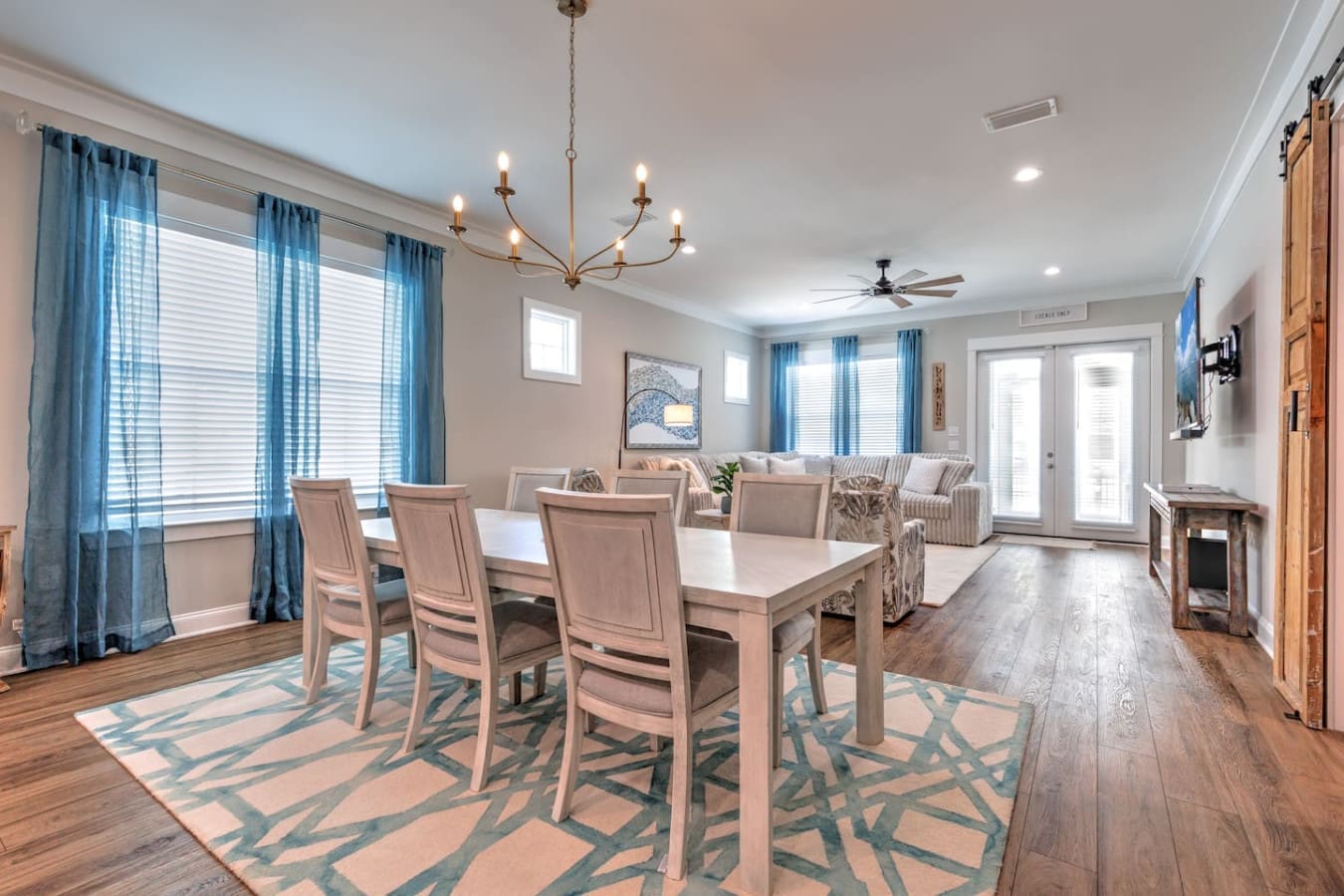 This open-concept space basically says "come hang out here" with the dining table, comfy seating, and those big bright windows all flowing together like the whole place was designed for people to actually gather and spend time together.
