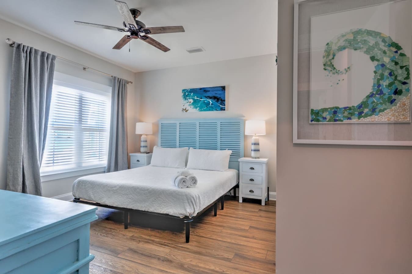 This bedroom is basically the ultimate coastal retreat with its calming turquoise headboard, crisp linens, and those big bright windows that'll have you waking up feeling like you're actually on vacation.