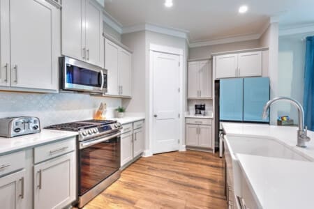 This kitchen has all the bells and whistles you'd actually want to use—think sleek white cabinetry, a proper gas range, and that huge island perfect for gathering while someone's cooking up something good.