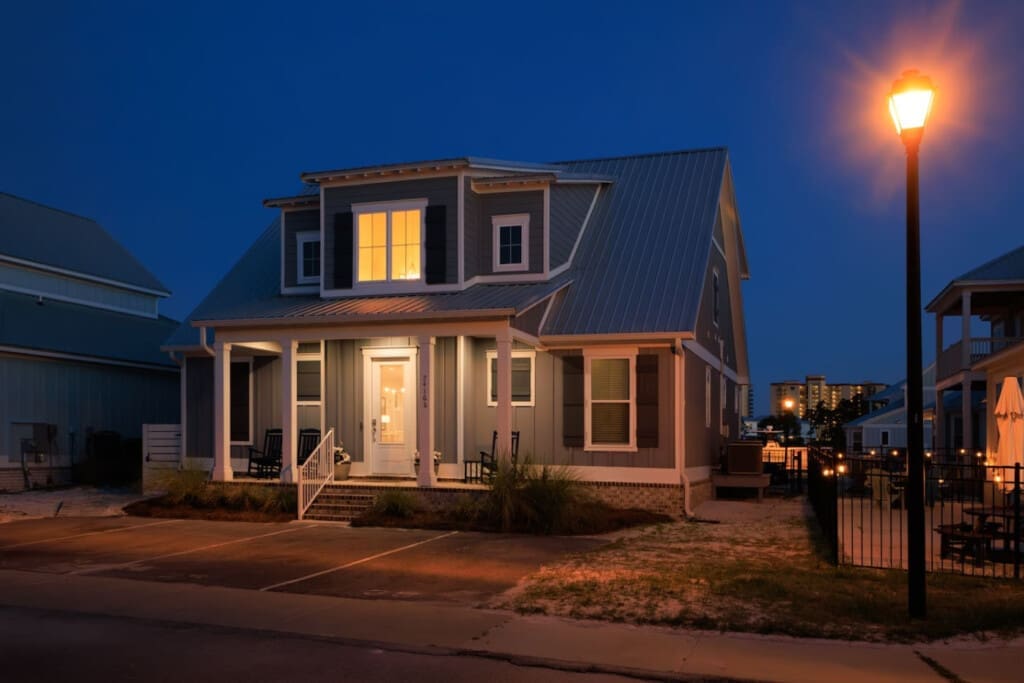 This cozy beach cottage lights up like a welcoming beacon at dusk, perfectly positioned for those sunset strolls and lazy evenings on the porch.