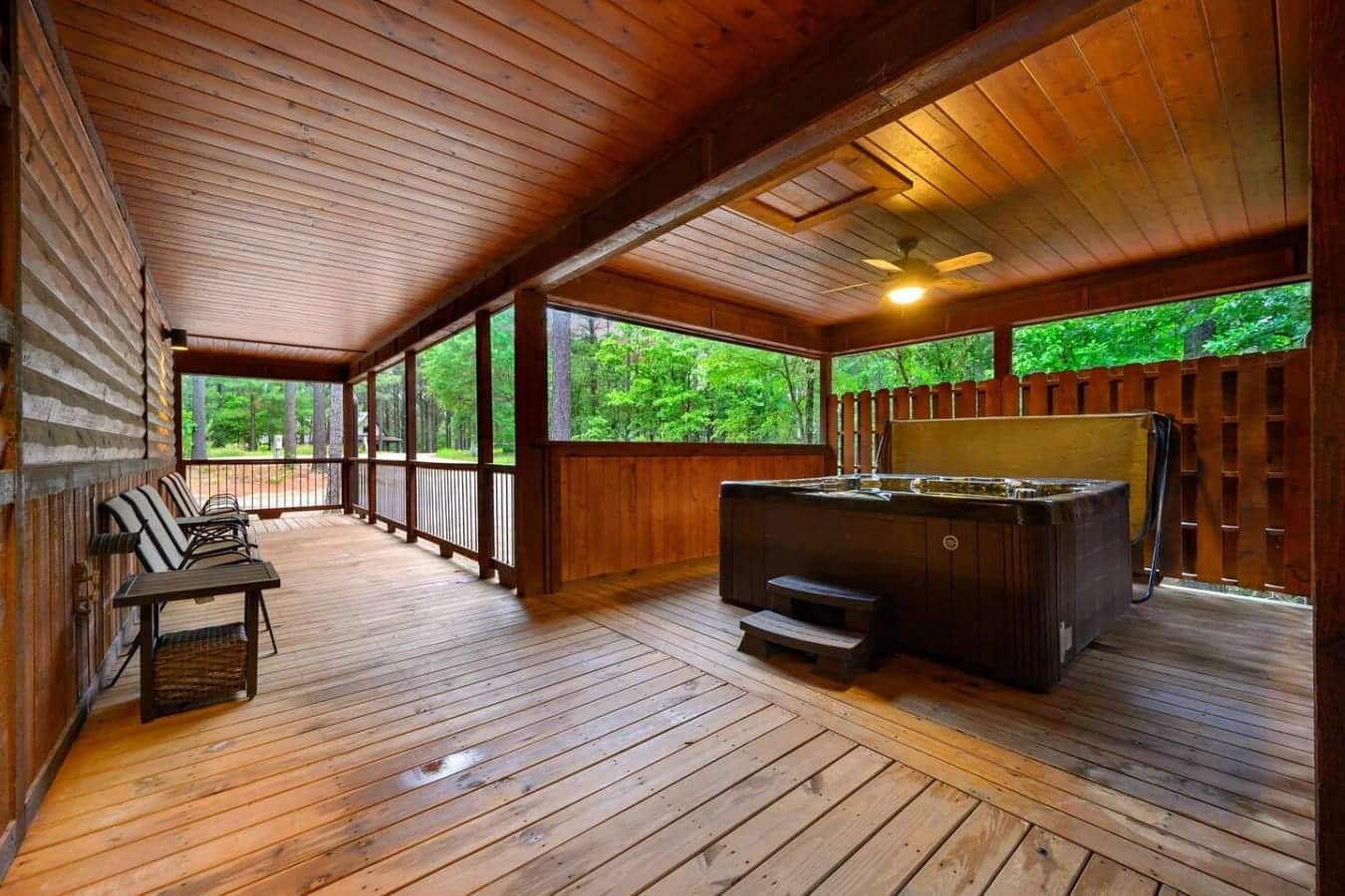 This covered deck is basically your own private resort—hot tub on one end, lounge chairs on the other, and enough wood and forest views to make you forget what day it is.