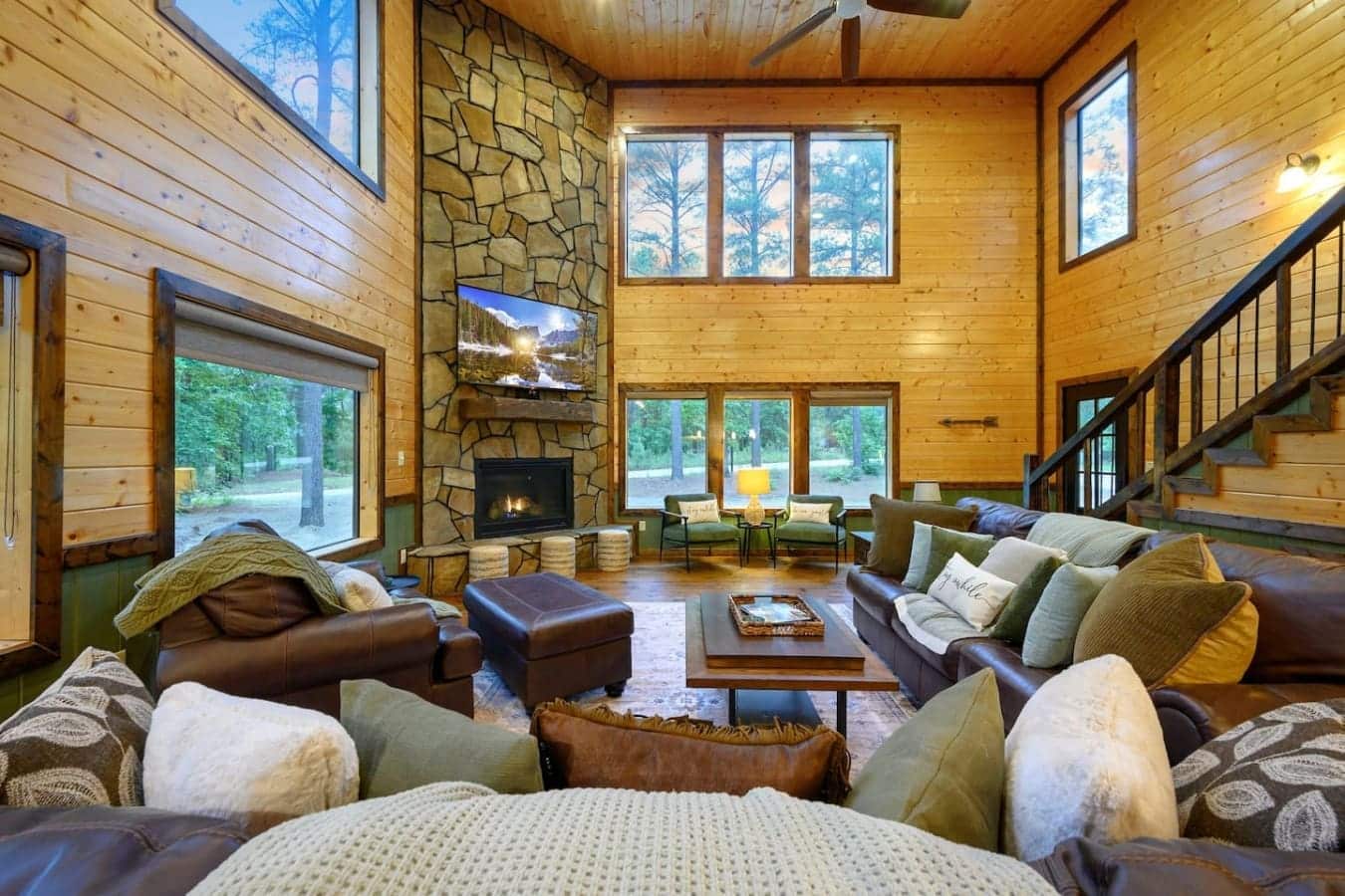 This living room basically says "forget the outside world exists" with a fireplace you can actually gather around, windows that frame the forest from every angle, and enough seating to sprawl out with your whole crew.