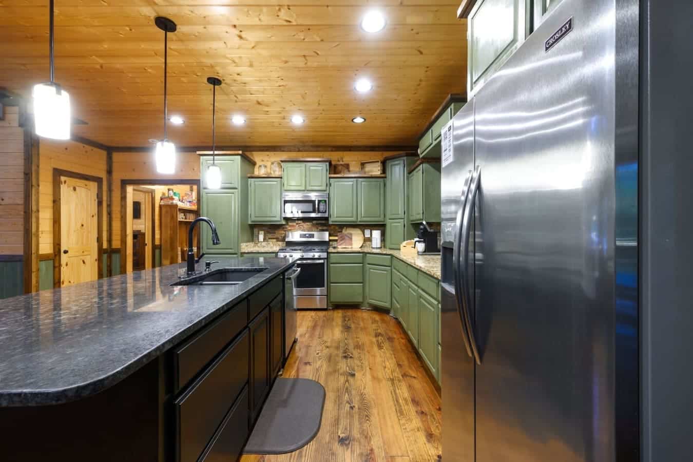 This kitchen has the green cabinets, stainless steel appliances, and granite counters that actually make you want to cook something instead of just ordering pizza.