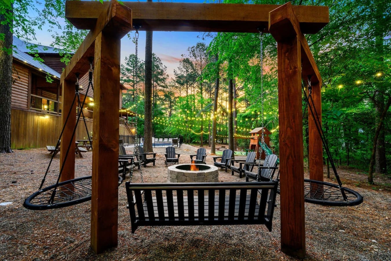 Picture yourself swinging right into this forest setup where you've got swings, a fire pit, Adirondack chairs, and enough twinkling lights strung through the trees to make you forget you ever had a curfew.