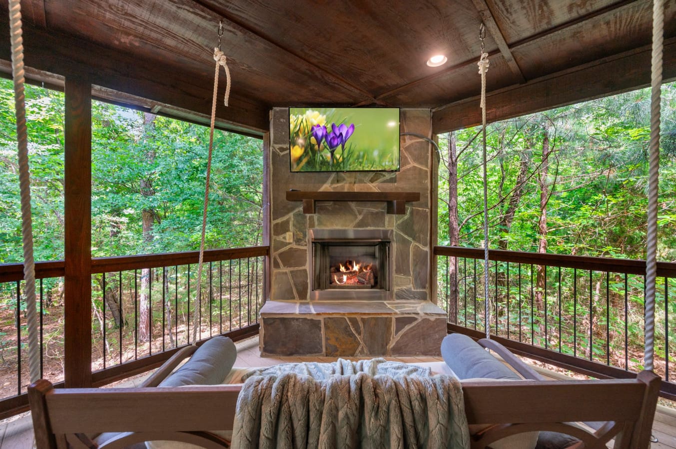 Outdoor living at its best—fireplace, TV, and a comfy swing.